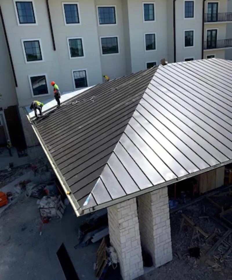 Crew installing standing seam metal roof panels on a commercial project in West Hempfield